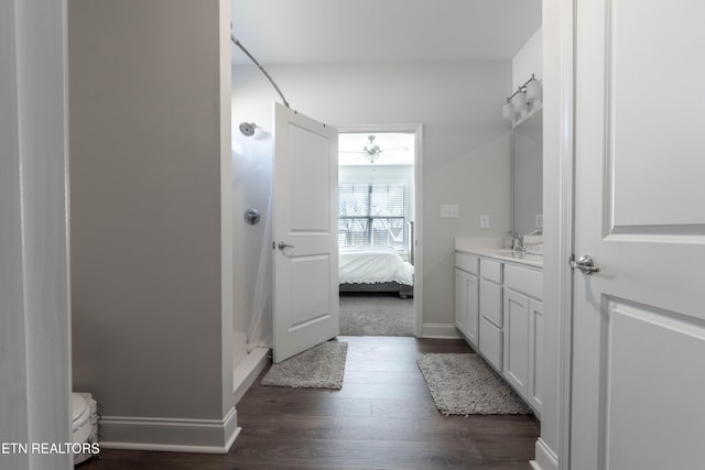 ensuite bathroom with a stall shower, connected bathroom, toilet, wood finished floors, and vanity