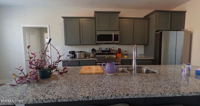 kitchen with stainless steel appliances, a sink, and light stone countertops