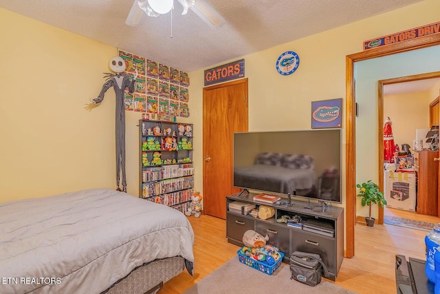 bedroom with light wood finished floors, ceiling fan, and a textured ceiling