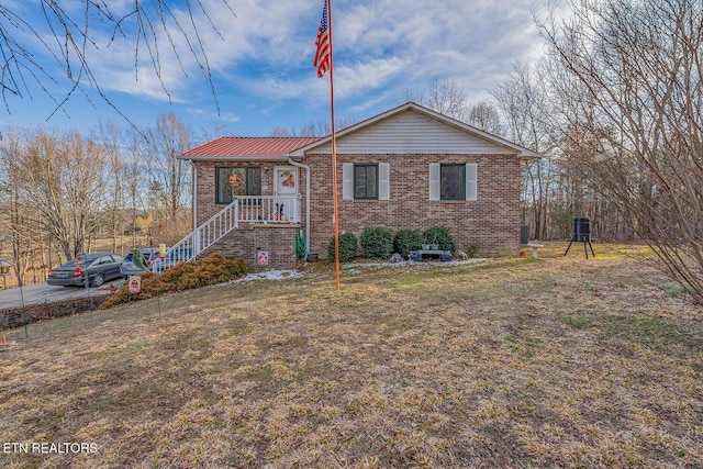 view of front facade with brick siding, metal roof, and a front lawn