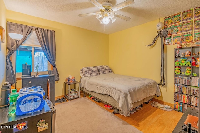 bedroom featuring baseboards, a ceiling fan, a textured ceiling, and wood finished floors