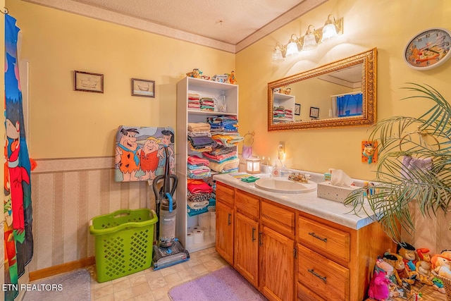 bathroom featuring ornamental molding, a textured ceiling, and vanity