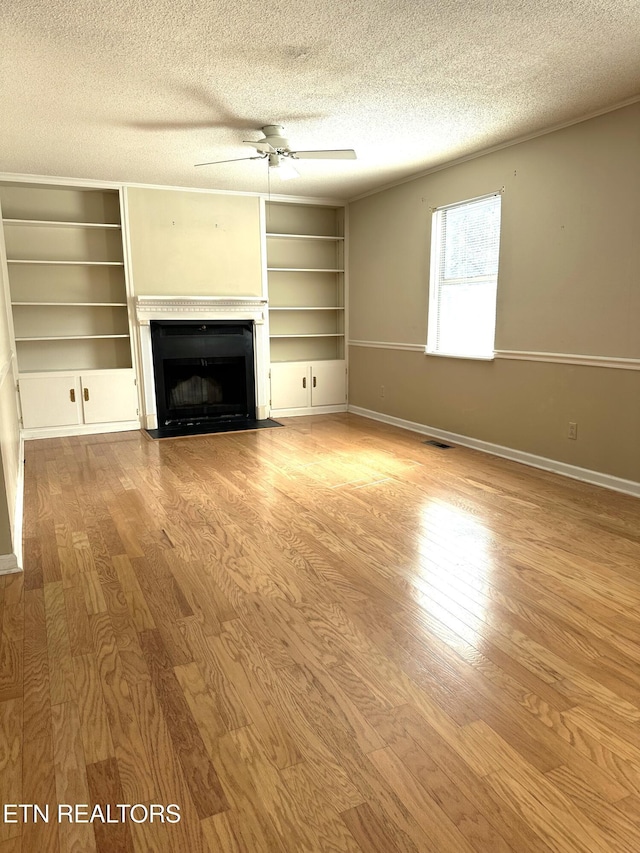 unfurnished living room featuring a fireplace with flush hearth, a ceiling fan, a textured ceiling, wood finished floors, and baseboards