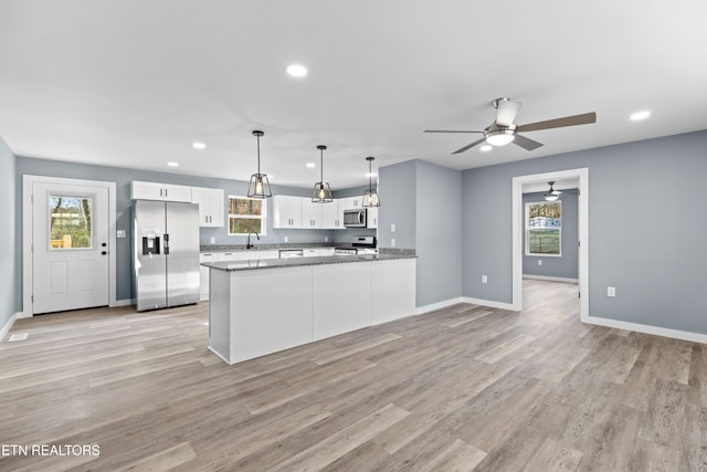 kitchen with decorative light fixtures, appliances with stainless steel finishes, stone countertops, white cabinetry, and a peninsula