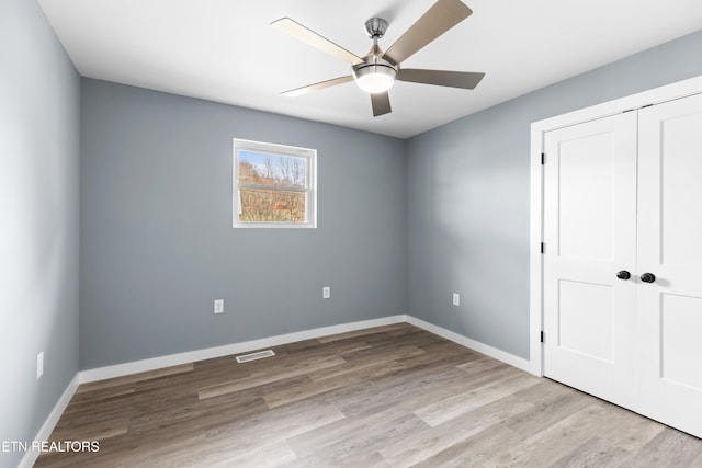 unfurnished bedroom featuring baseboards, a closet, visible vents, and light wood-style floors