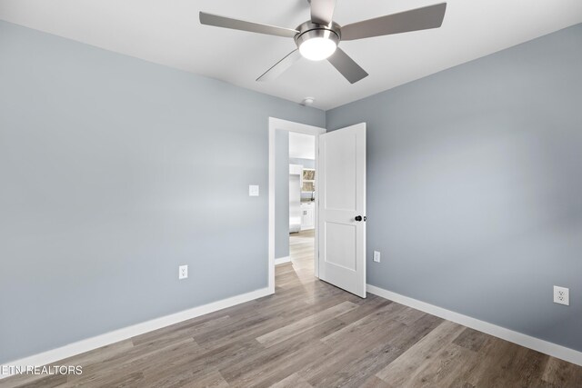 empty room with baseboards, a ceiling fan, and light wood-style floors