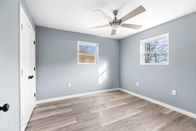 spare room with baseboards, ceiling fan, and light wood finished floors