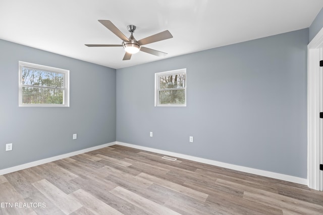 empty room featuring light wood finished floors, plenty of natural light, and baseboards