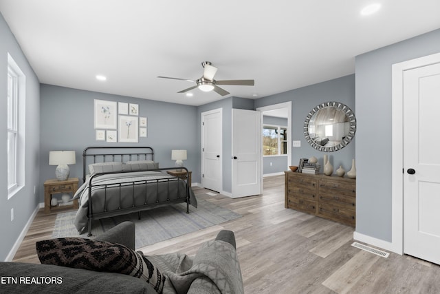 bedroom featuring ceiling fan, visible vents, light wood-style flooring, and baseboards