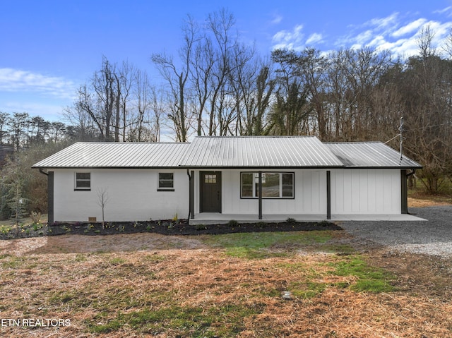 ranch-style home featuring a porch and metal roof