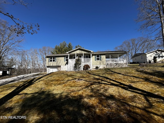 view of front facade with a porch, a front yard, driveway, and an attached garage