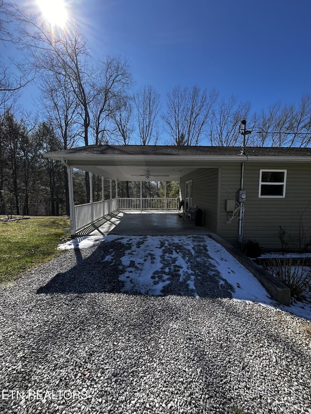 view of parking featuring an attached carport and gravel driveway