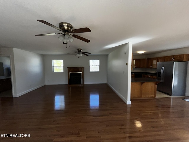 unfurnished living room with dark wood-style flooring, a fireplace, and baseboards