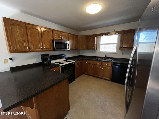 kitchen featuring a peninsula, dark countertops, appliances with stainless steel finishes, and a sink