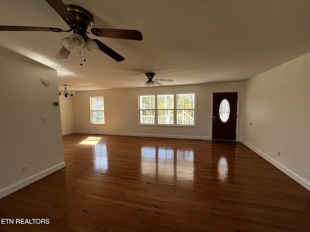 interior space featuring dark wood-style floors, baseboards, and ceiling fan with notable chandelier