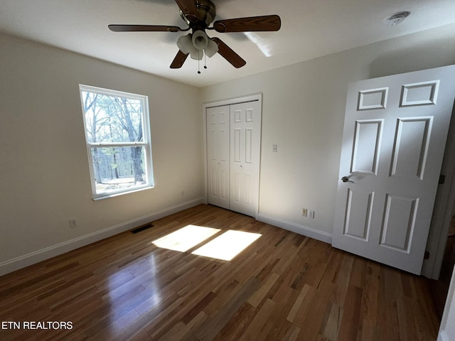 unfurnished bedroom featuring visible vents, dark wood finished floors, and baseboards