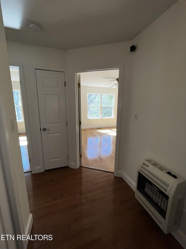 hall with dark wood-style floors, baseboards, and heating unit