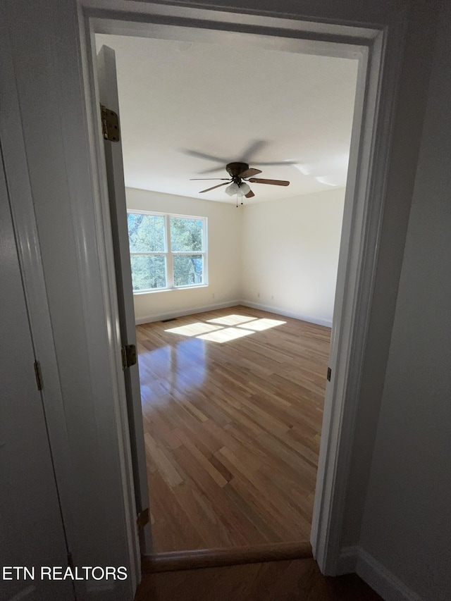 unfurnished room featuring ceiling fan, baseboards, and wood finished floors