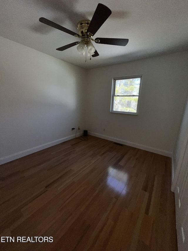 spare room featuring dark wood-style flooring and baseboards