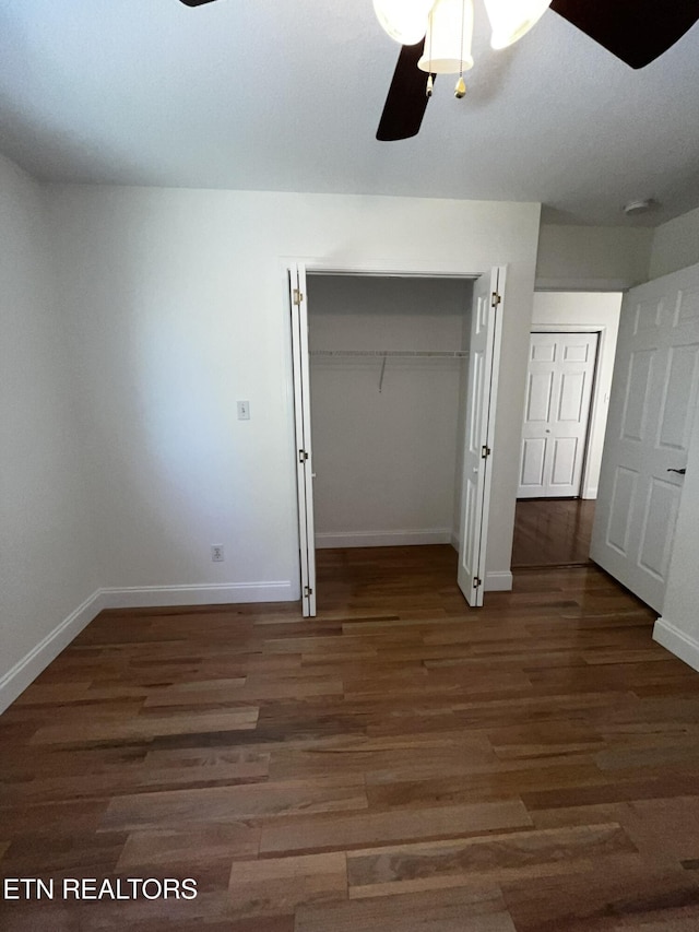 unfurnished bedroom with ceiling fan, a closet, dark wood finished floors, and baseboards