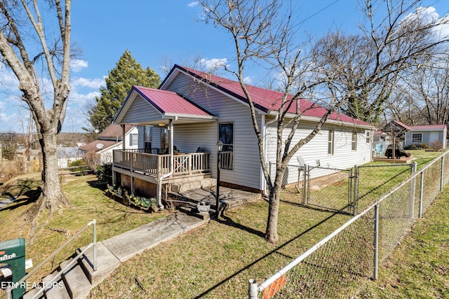 view of front of property featuring a deck, metal roof, a front yard, and a gate