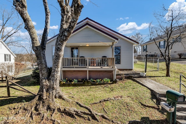 back of property with a lawn, fence, and a gate