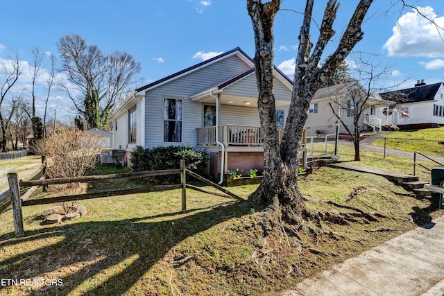 view of front of home with a porch, a front yard, and fence