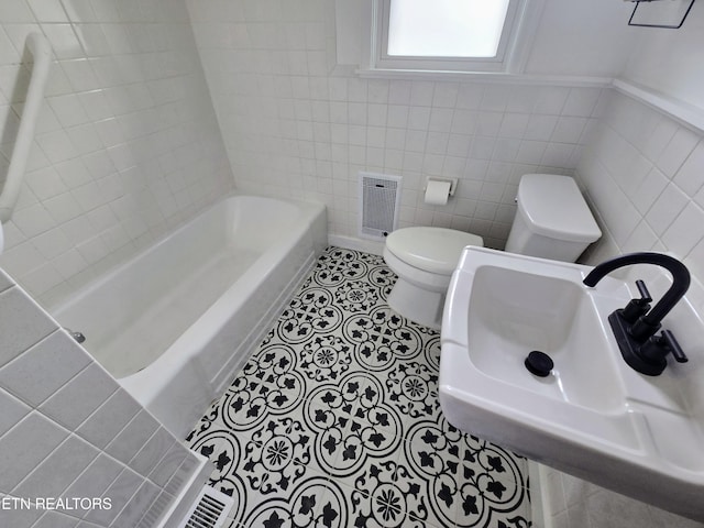 bathroom featuring tile patterned flooring, toilet, visible vents, tile walls, and a bath