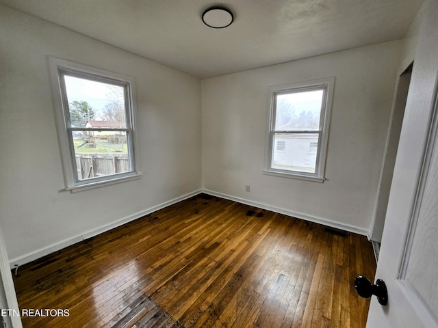 unfurnished room featuring dark wood-style floors and baseboards