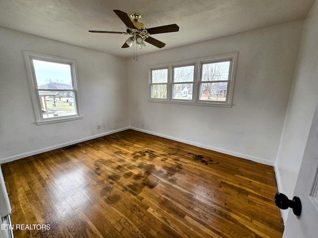 spare room with visible vents, baseboards, dark wood finished floors, and a ceiling fan