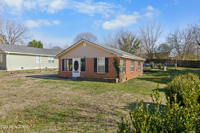 back of house with brick siding, a lawn, and fence