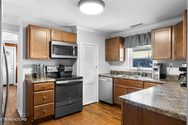 kitchen with a sink, visible vents, appliances with stainless steel finishes, dark countertops, and dark wood finished floors