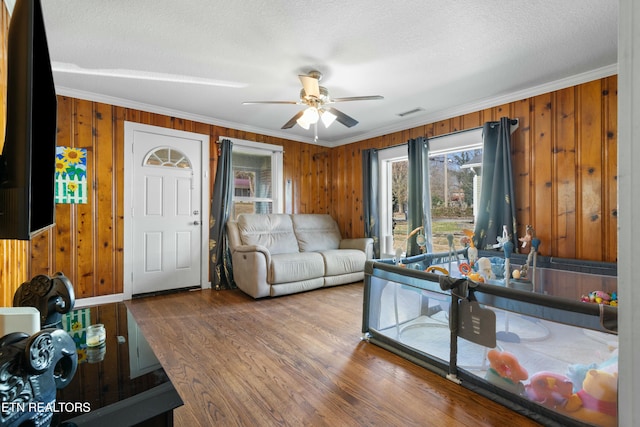 living area featuring wood walls, crown molding, and wood finished floors