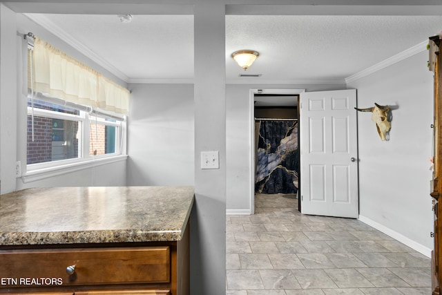 kitchen featuring a textured ceiling, ornamental molding, and baseboards