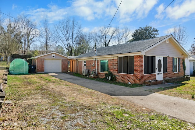 single story home with an outbuilding, a garage, brick siding, driveway, and a front yard