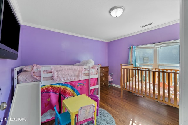 bedroom featuring ornamental molding, wood finished floors, visible vents, and baseboards