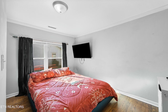 bedroom featuring dark wood-style floors, baseboards, visible vents, and crown molding