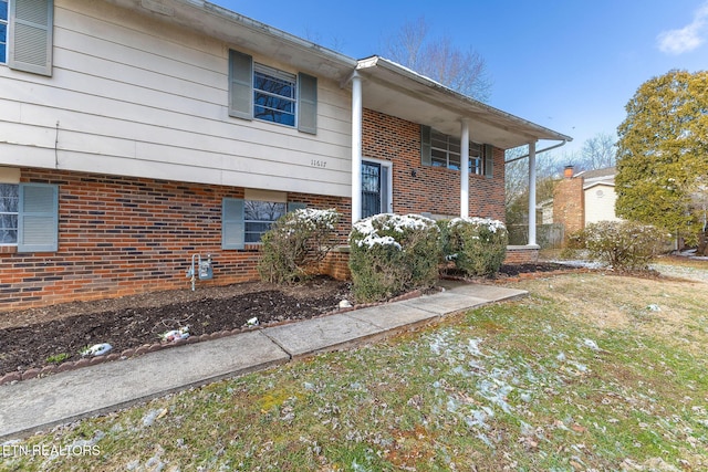 view of front of property featuring brick siding and a front lawn