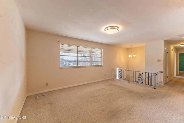 spare room featuring baseboards, visible vents, carpet flooring, and an inviting chandelier