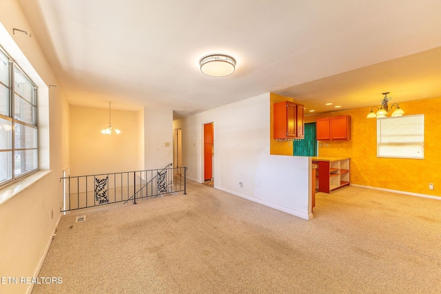 unfurnished room featuring a chandelier, light carpet, and baseboards