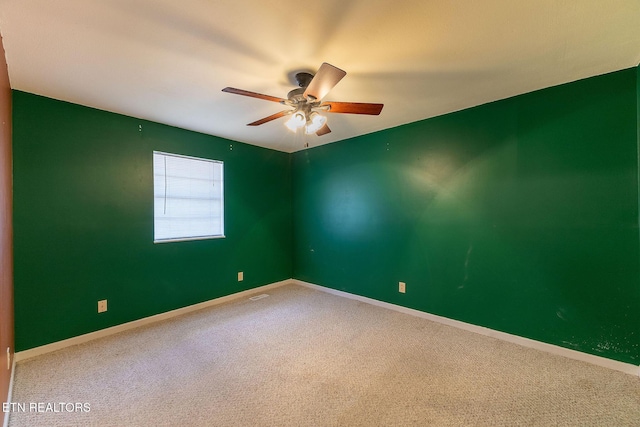 carpeted spare room with a ceiling fan and baseboards