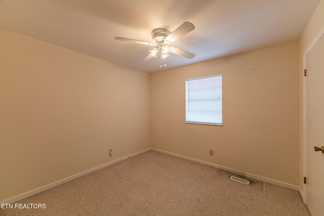 carpeted empty room with baseboards, visible vents, and a ceiling fan