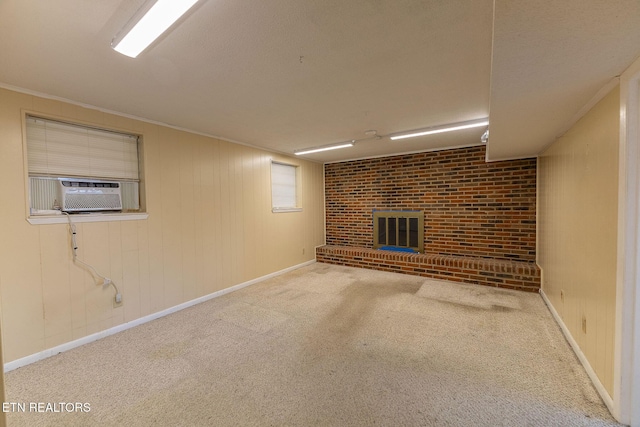 finished basement with baseboards, ornamental molding, cooling unit, carpet floors, and a fireplace