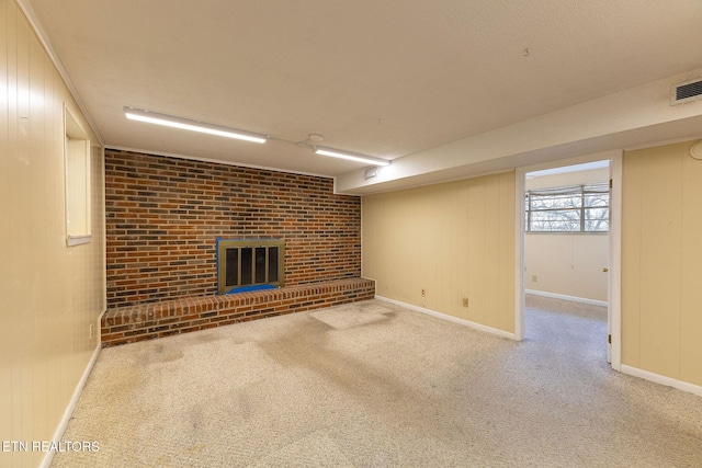 basement featuring brick wall, a brick fireplace, and light colored carpet