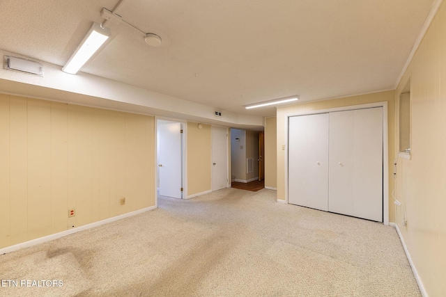 finished basement with baseboards, visible vents, and light colored carpet