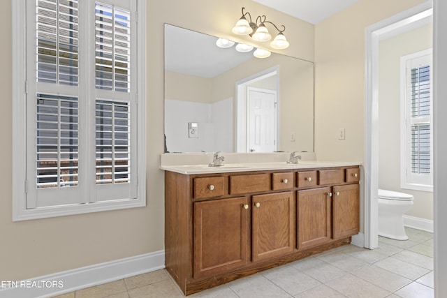 bathroom with double vanity, baseboards, toilet, tile patterned flooring, and a sink