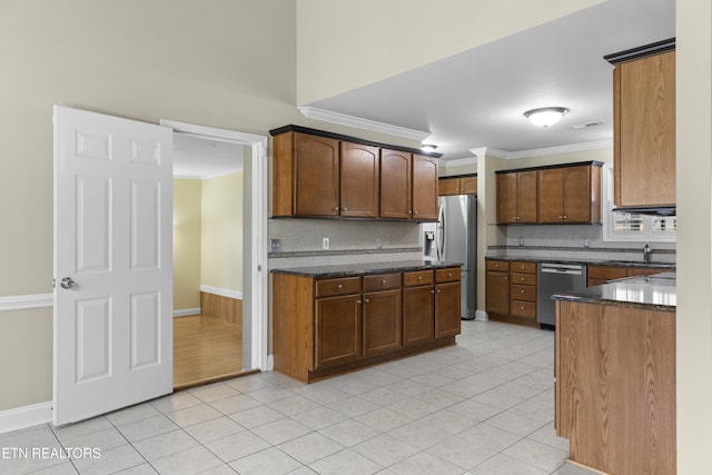 kitchen featuring ornamental molding, appliances with stainless steel finishes, dark stone counters, and light tile patterned floors