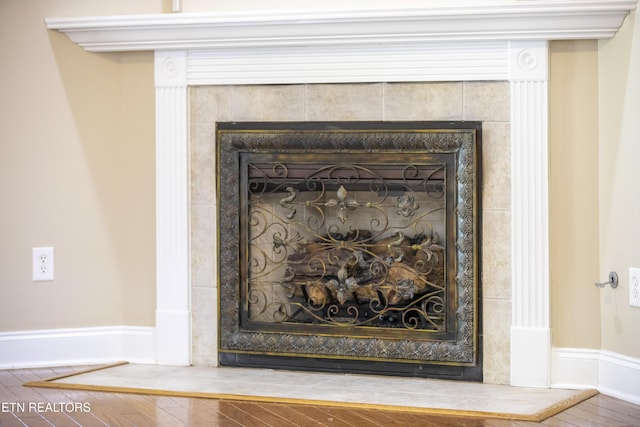 interior details featuring a tiled fireplace and wood finished floors