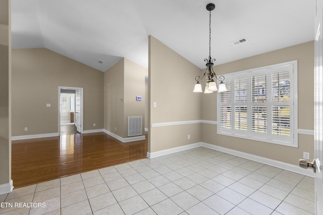 spare room with vaulted ceiling, light tile patterned floors, visible vents, and an inviting chandelier