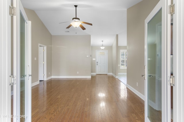 interior space featuring vaulted ceiling, wood finished floors, a ceiling fan, and baseboards